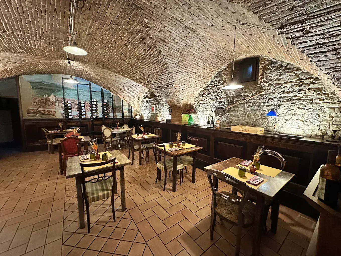La sala principale: volte a crociera di mattoni, tavoli con tovagliette gialle e tovaglioli a quadretti rossi, lampade smaltate accese.